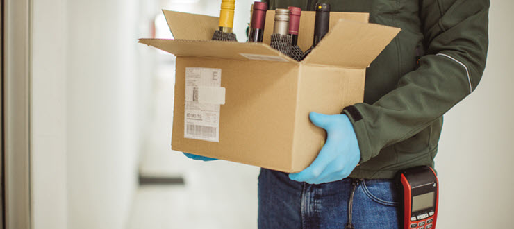 Man delivering box of alcohol bottles with POS machine